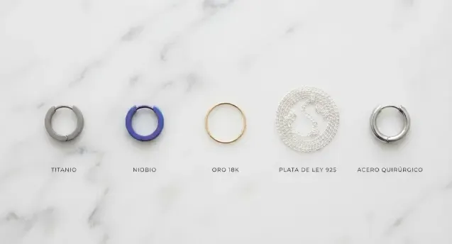 Comparativa visual de metales para joyas hipoalergénicas: titanio, niobio, oro, plata y acero